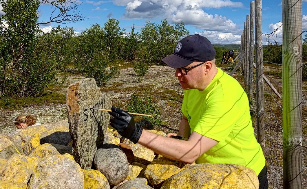 Henkilö tekee merkintöjä rajakiveen.