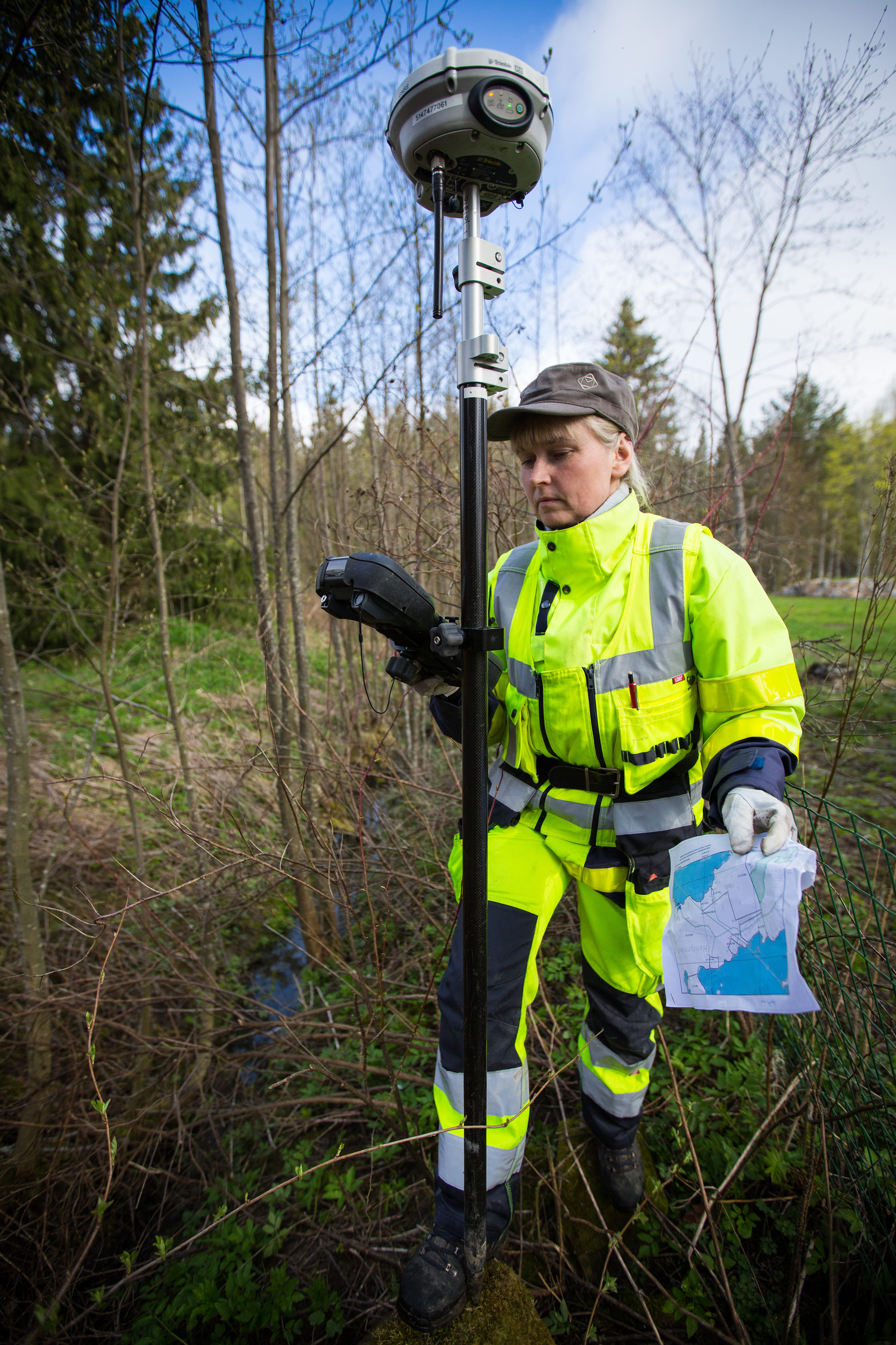 Maanmittari lukee mittauslaitteistoa metsässä.