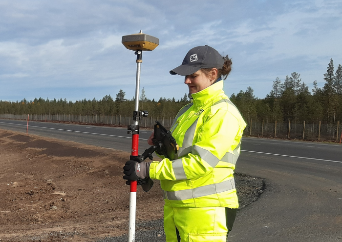 Kartläggaren Jonna står utomhus i arbetskläder med mätinstrument.