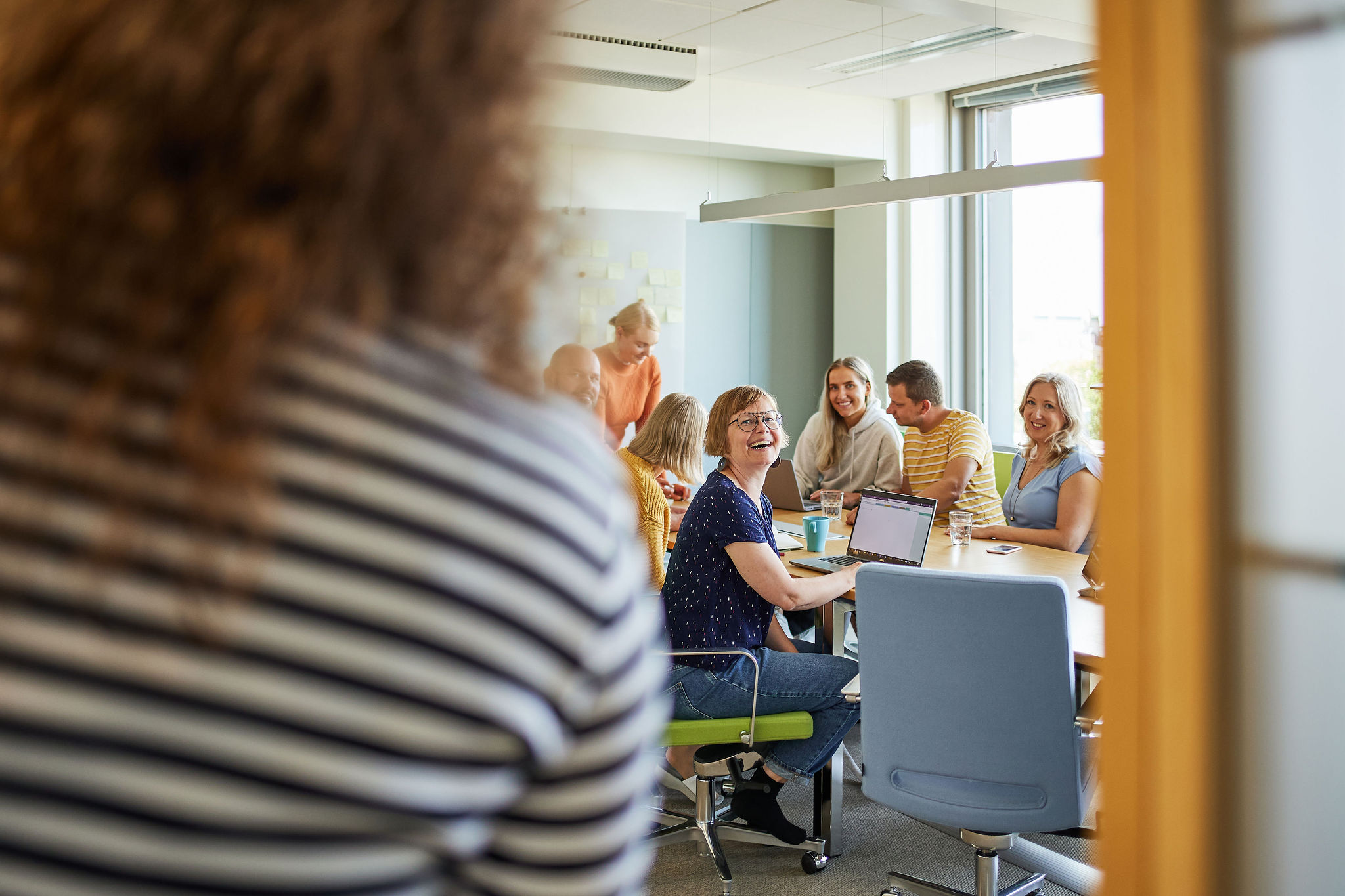 A person walking into a conference room full of smiling NLS employees.