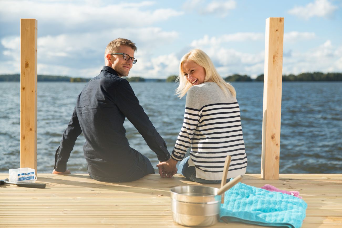 Man and woman sitting on a pier by the lake.