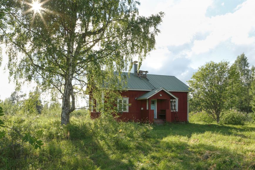 Kuvassa kesämökki vehreässä maisemassa