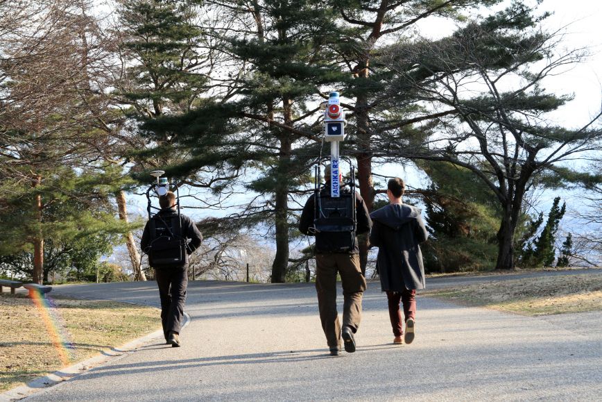Two researchers walking with backpack laser scanners.