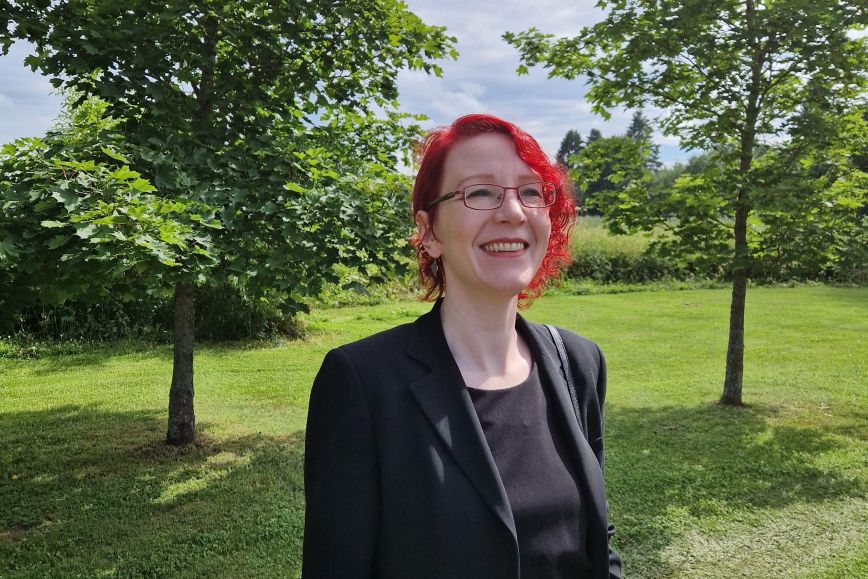 Anna hymyilee vehreässä maisemassa.