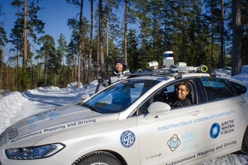 Itseohjautuva auto lumisessa metsämaisemassa