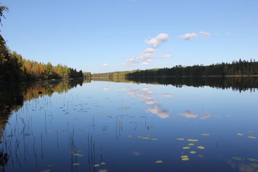 Det är vindstilla och sjöns vattenyta reflekterar himlen och molnen