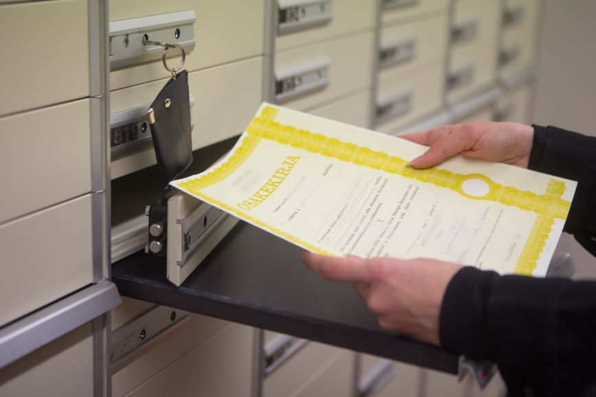 Ihmisellä käsissään aito paperinen osakekirja