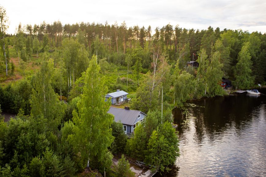 Mökkejä rannalla metsän keskellä
