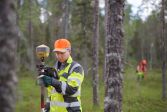 Mies mittaa rajan paikkaa metsässä.