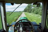 Traktori ajaa maaseudulla pitkin kesäistä kylätietä. 