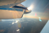 Maata ja vesistöä auringonpaisteessa ylhäältä lentokoneesta kuvattuna.