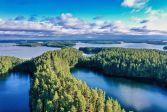 Aerial view of a lake landscape with blue water and islands covered in green forests. Clouds on the horizon.