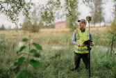 Mies seisoo pientareella keltaisessa liivissä ja kädessään mittalaite