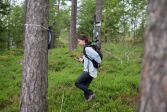 Nainen kävelee metsässä tutkimuslaitteen kanssa.