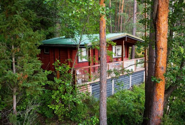 Punainen kesämökki metsän keskellä.
