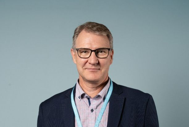 Puolivartalokuvassa puku päällä Pasi Patrikainen katsoo kameraan