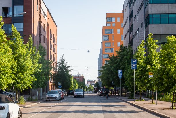  A street with apartment buildings and parked cars along it.