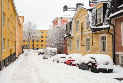 Talvinen katu, jonka varrella lumeen peittyneitä autoja
