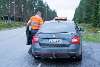 Maanmittauslaitoksen työntekijä on menossa sisälle autoon.