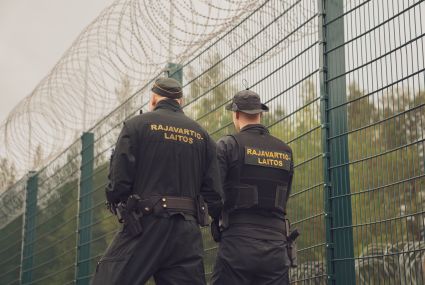 Kaksi rajavartiolaitoksen työntekijää selin aidan edessä