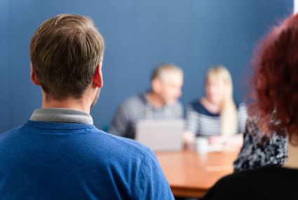 sinipaitainen mies ja punatukkainen nainen istuvat selin kameraan