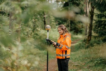Maanmittausinsinööri metsässä mittauslaitteiden kanssa