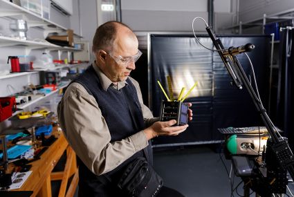 Kuvassa tutkimusryhmäpäällikkö Jouni Peltoniemi valmistelee KitSat-mallisatelliittia mittauksia varten. 