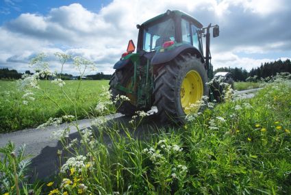 En traktor kör på en väg mellan två åkrar.